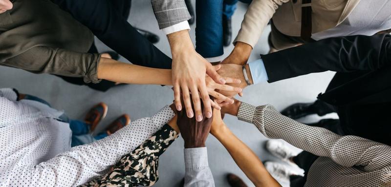 Hands in the middle hands in the middle of circle of people wearing smart clothing