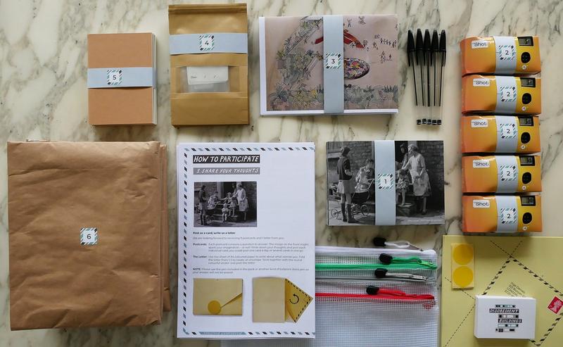 Camera,s bags, postcards and instructions laid out on a table