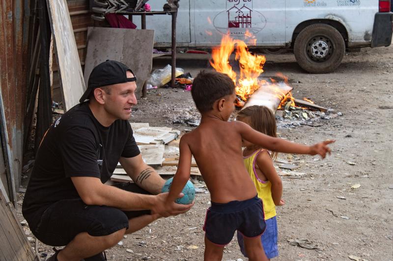 gabriel in the field with two children, small fire and van in background