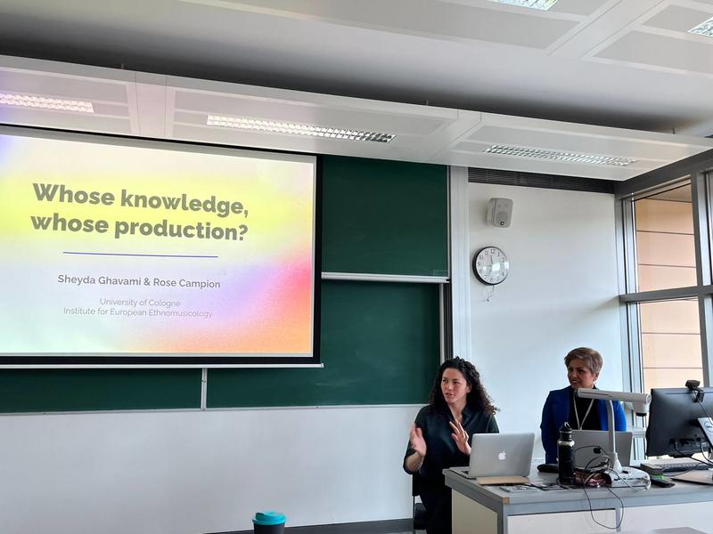 Rose and sheyda presenting Two women at a desk with a powerpoint behind them