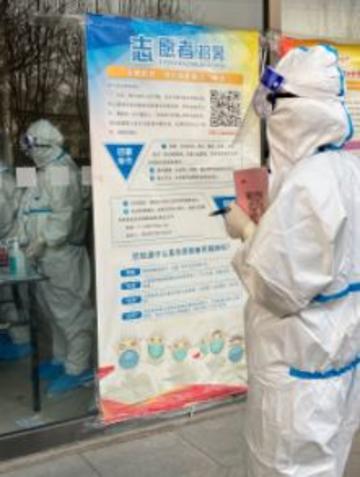 Siyu tang A staff member dressed in hazmat suit, standing in front of a poster with an illustration of people dressed similarly. (Photo by author.)