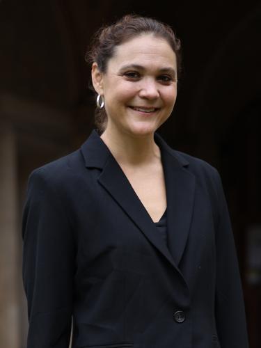A woman in a black jacket outside an old stone building