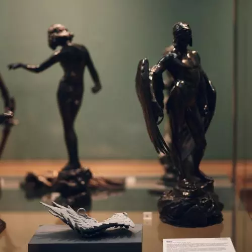 A small centipede like sculpture in a case of classical bronze statues
