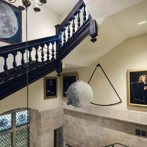 A hanging sculpture of a moon near a large pastel illustration of the moon