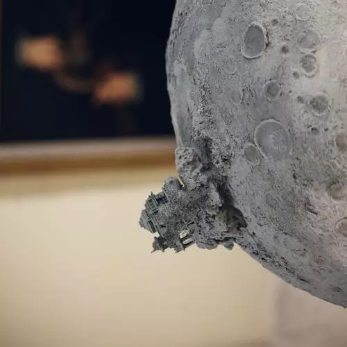 A close up of small building with trees on a sculpture of an imagined moon.