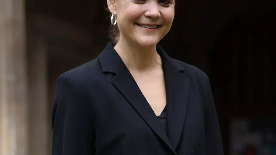 A woman in a black jacket outside an old stone building