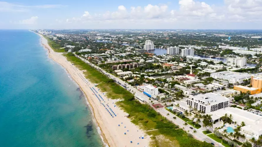 A view from above of Delray Beach, Florida; a long sandy beach next to an expansive town. 