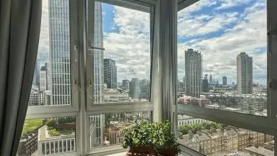 View from a living room's corner window showing sky scrapers and tower blocks on a sunny day