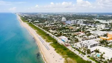 A view from above of Delray Beach, Florida; a long sandy beach next to an expansive town. 