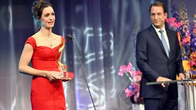 Woman in red dress collecting award on stage