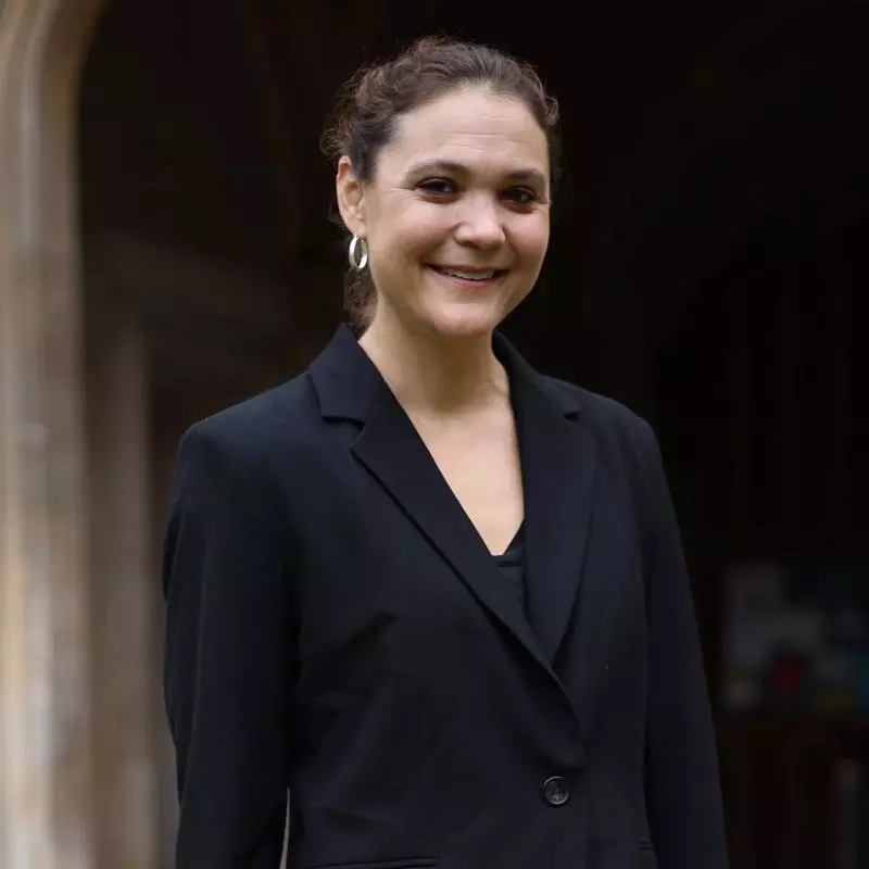 A woman in a black jacket outside an old stone building