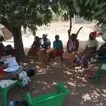 group of black women talking in circle in shade of tree