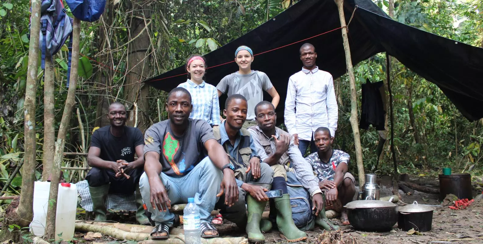 A group of men and women at a campsite in the forest