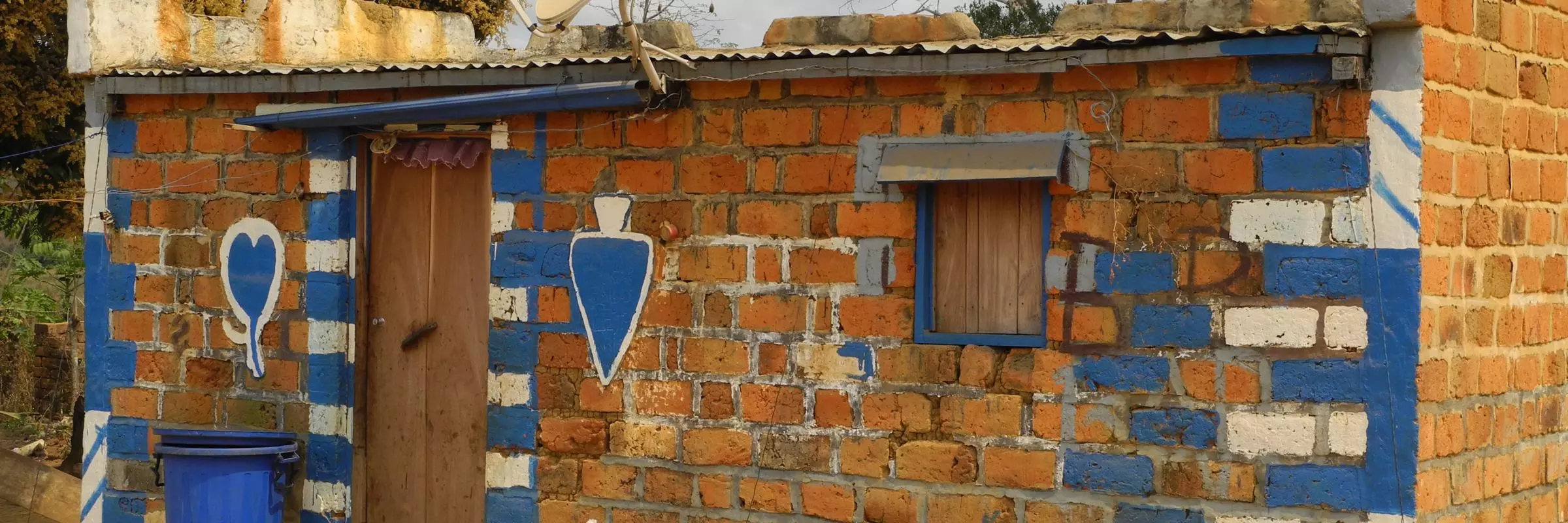 A small house painted blue and white with a corrugated iron roof 