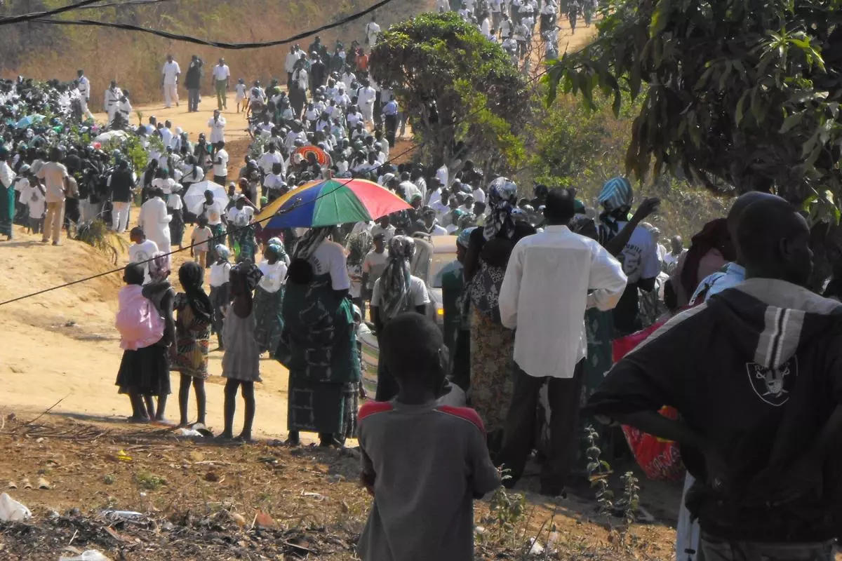 A long line of pilgrims filling a dusty track curving off into the distance