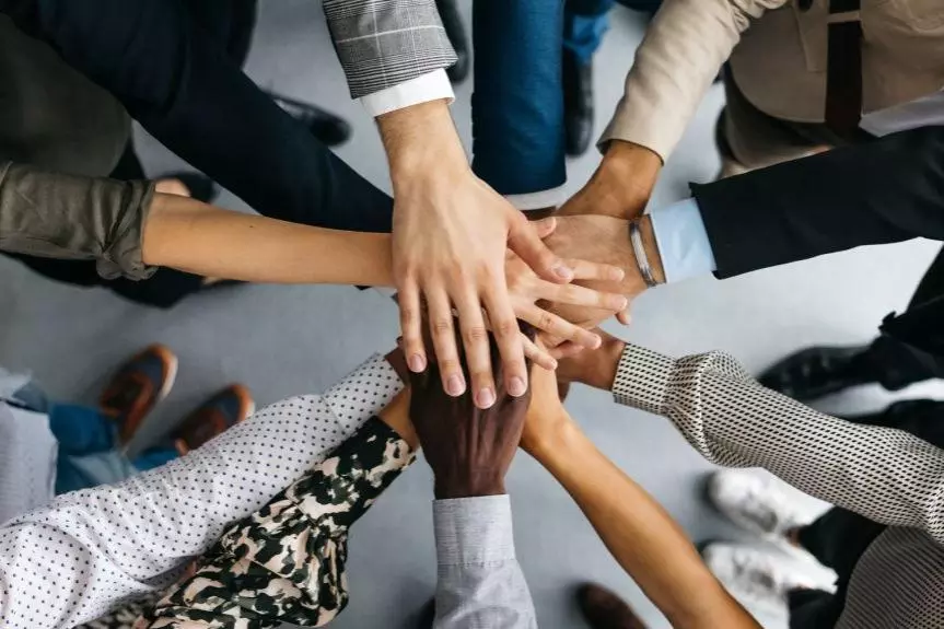 hands in the middle of circle of people wearing smart clothing 