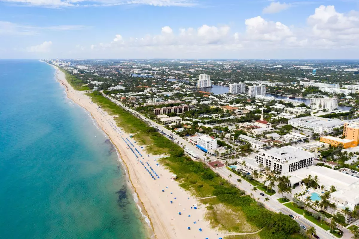 A view from above of Delray Beach, Florida; a long sandy beach next to an expansive town. 