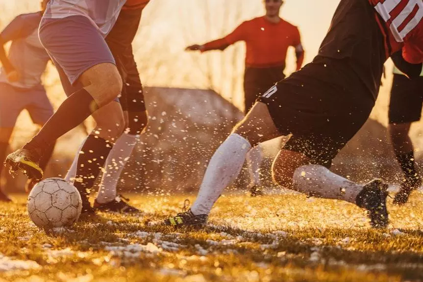 close up of feet and legs of footballers in autumn sunshine