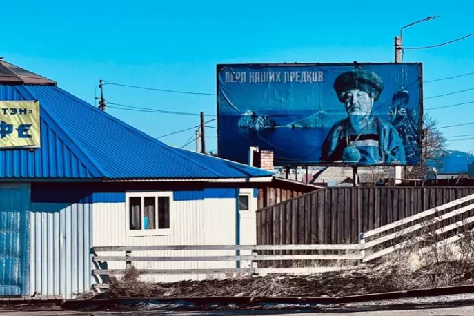 large billboard next to house showing man in fur hat